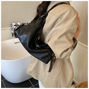 Detailed view of a soft black leather tote bag featuring silver hardware and fine texture