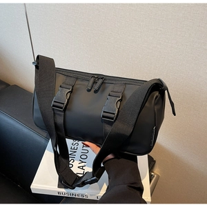 Detail of black cylinder nylon crossbody bag with dual buckles and wide strap