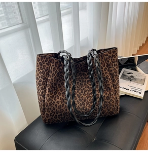 Detail of leopard print tote bag with thick black braided handles on leather seat