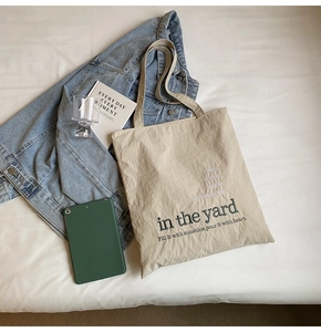Detailed top view of off-white canvas tote bag with black text and casual daily essentials