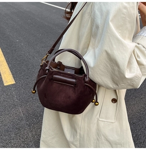 Close-up of a brown suede bucket bag with drawstring and vintage gold hardware accents