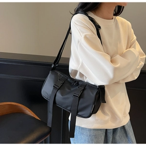 Detail of black nylon crossbody bag with dual buckles and adjustable strap on a model