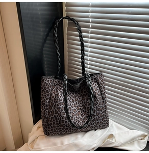 Macro detail of leopard print tote bag featuring black braided leather shoulder straps