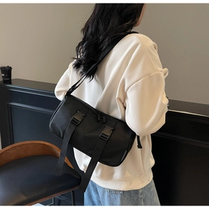 Side view of a black nylon crossbody bag with buckle detail worn for daily commute