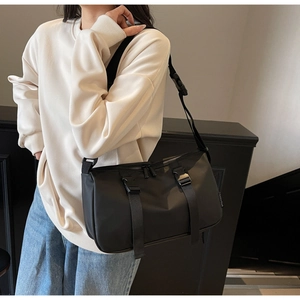 Detail of black nylon crossbody bag featuring quick-release buckles and matte texture