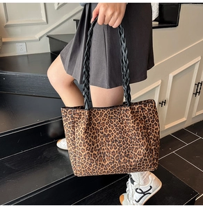 Detailed close-up of large leopard print tote bag with black woven handles and fabric texture