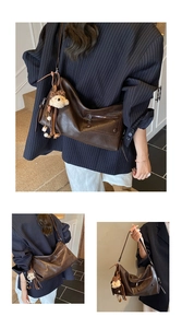 Detail of dark brown faux leather tote bag with plush bear charm and tassel on shoulder strap