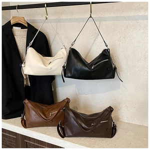 Detail of four retro soft leather crescent bags with decorative zippers and adjustable straps