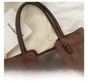 Detail of brown tote bag showing smooth leather texture and braided side stitching