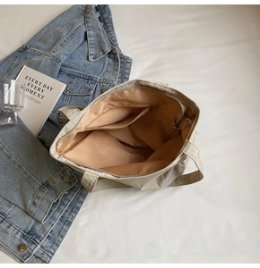 Detailed interior view of beige canvas tote bag showing zipper pocket and spacious lining