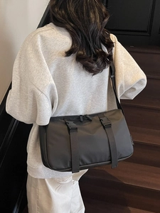 Lightweight black nylon crossbody bag with dual buckles shown on a model's back