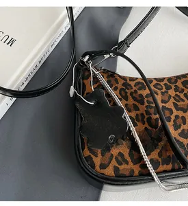 Detail of leopard print faux fur bag with black bear charm and silver chain strap