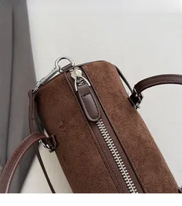 Top view detail of high-quality silver metal zipper on a dark brown suede cylinder bag