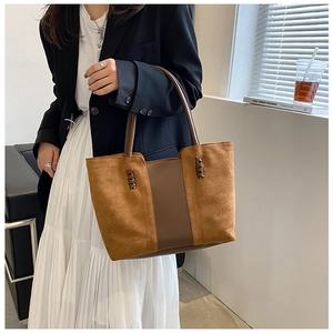 Detail of vintage brown suede tote bag with woven stitching held by a model in office attire