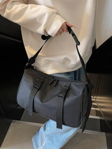 Women's black nylon crossbody bag featuring wide adjustable strap and buckle details