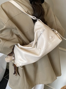 Elegant cream faux leather tote bag with brown bear charm and metal zipper detail