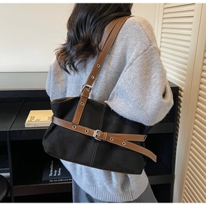 Close-up of black canvas tote bag with brown leather straps and silver metal buckle detail