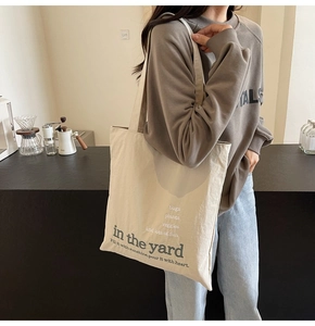 Detail of a beige canvas tote bag with poetic print styled in a cozy cafe setting