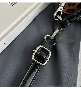 Detail of adjustable black patent leather strap with silver alloy buckle on crescent bag