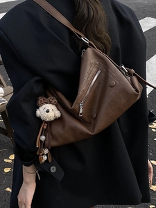 Chic brown leather tote bag with plush dog charm over a black blazer for work