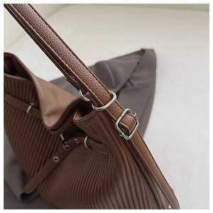 Detail of brown lychee texture tote bag with vertical pleats and silver metal buckle