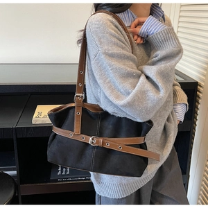 Close-up of black matte tote bag featuring vintage brown leather belt decorative straps