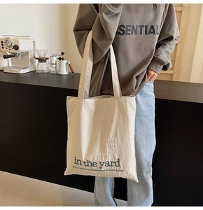 Detail of high-density cream canvas tote bag showing green botanical lettering print