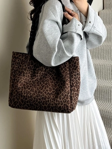 Large leopard print faux suede tote bag with woven shoulder strap shown on a model