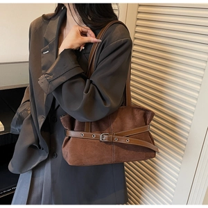 Brown suede shoulder bag with dark leather strap and buckle detail on female model