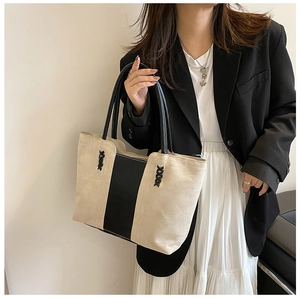 Detail showing cross-lace stitching on canvas tote bag with black strap contrast