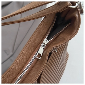 Detail shot of brown lychee leather shoulder bag with silver zipper and pleated side