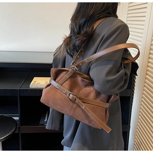 Close-up of brown suede and leather hobo bag featuring silver buckle and strap details