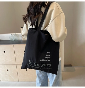 Detail showing the white embroidered text on black canvas of this large tote bag