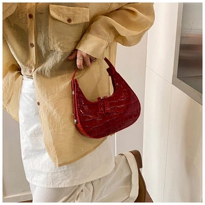 Detailed view of red crocodile-patterned crescent bag styled with an elegant outfit