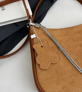 Detail of brown suede shoulder bag featuring silver chain and cute bear charm pendant