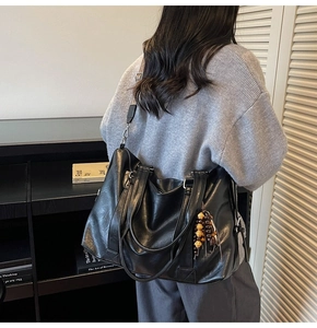Vue détaillée d'un grand sac cabas en cuir noir souple avec une large bandoulière tissée