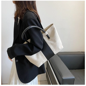 Detail of minimalist black and white canvas tote bag worn by a model in a modern setting