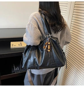 Détail du grand sac cabas noir avec bandoulière tissée et perles décoratives en bois