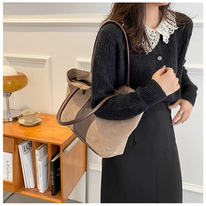 Detail of vintage suede tote bag in khaki brown with leather handles on a wooden table