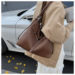 Detail of caramel pleated leather shoulder bag with adjustable strap and metal buckle