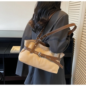 Detailed side view of two-tone tote bag with brown leather straps on woman's shoulder