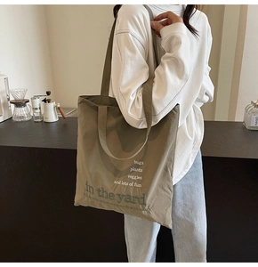 Close-up of olive canvas tote bag with nature-themed embroidery and wide shoulder strap