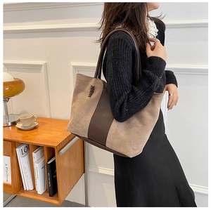 Detailed view of brown suede tote bag featuring contrast leather strap and small metal logo