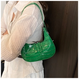 Close-up of bright green crocodile pattern faux leather crescent underarm bag on model
