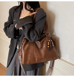 Détail d'un grand sac cabas marron avec glands perlés ethniques et bandoulière tissée