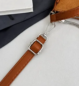 Close-up of silver alloy buckle and lobster clasp on brown leather shoulder bag strap