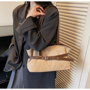 Detail of beige suede tote bag with brown leather straps shown on model shoulder