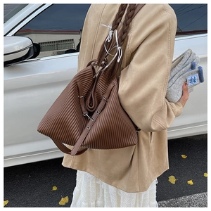 Detail of a brown pleated shoulder bag showing accordion texture and leather strap