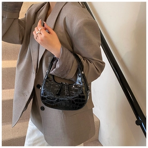 Detail of black crocodile texture hobo bag with glossy finish and silver hardware