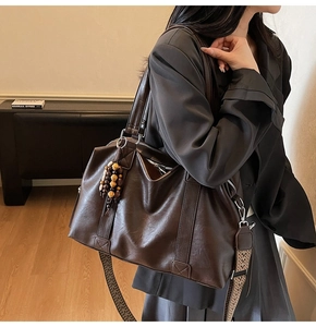 Détail d'un sac cabas marron avec pendentif à glands et bandoulière large à motifs